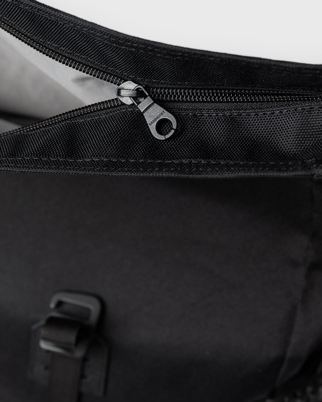 Sandqvist ICON Rolltop Backpack 14" noir — détail de la fermeture éclair supérieure et de la doublure.