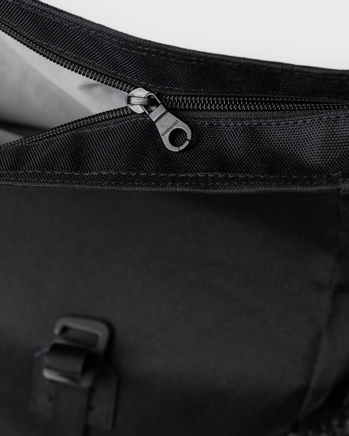 Sandqvist ICON Rolltop Backpack 14" noir — détail de la fermeture éclair supérieure et de la doublure.