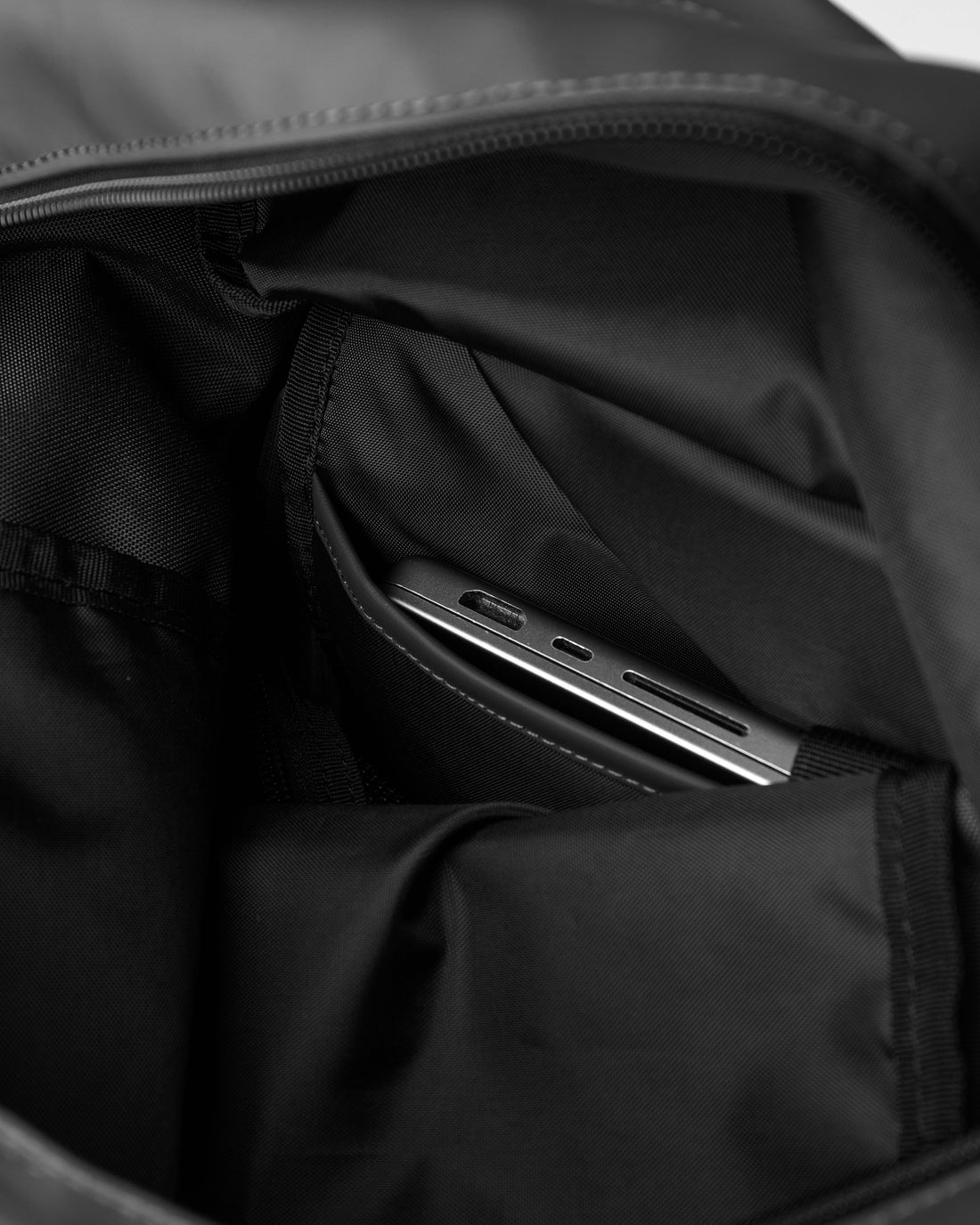 Sandqvist STREAM Rolltop Backpack L noir — vue du compartiment rembourré avec un ordinateur portable pour illustrer le rangement.