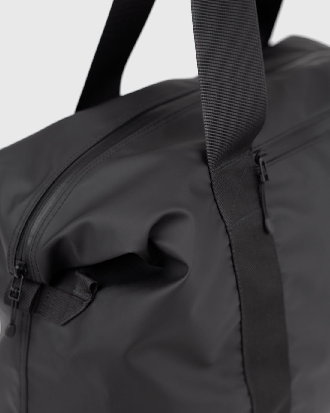 Sandqvist STREAM Weekender Bag noir — détail de l’extrémité latérale et de sa fixation.