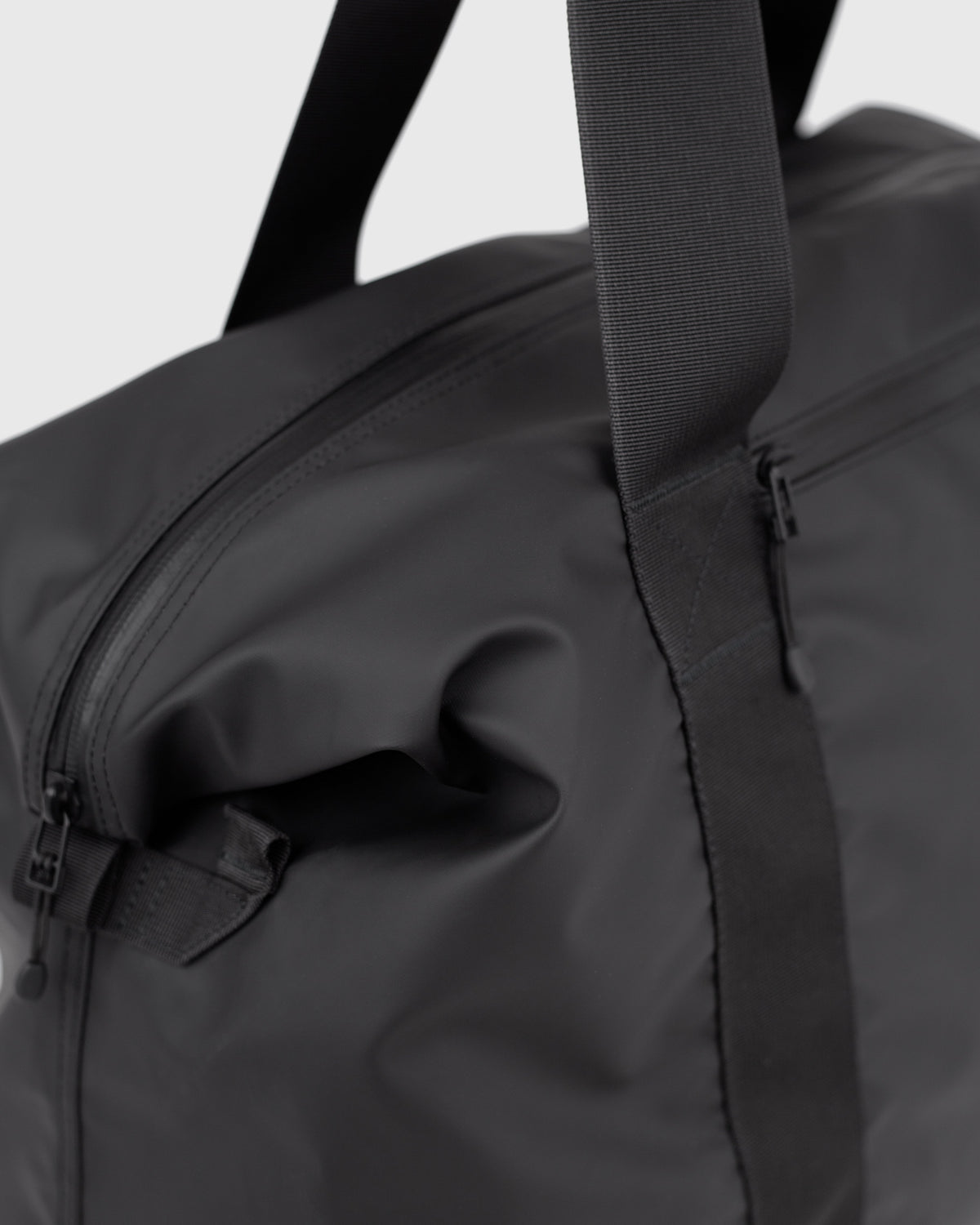 Sandqvist STREAM Weekender Bag noir — détail de l’extrémité latérale et de sa fixation.