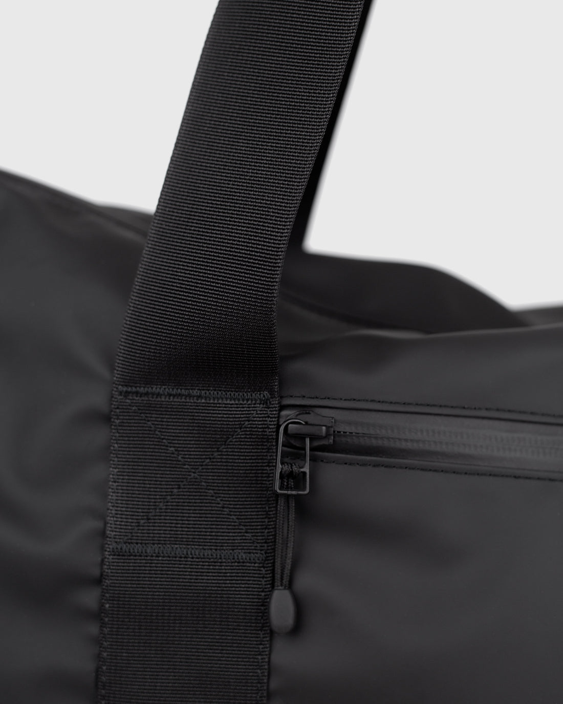Sandqvist STREAM Weekender Bag noir — détail de la sangle et de la poche frontale zippée.