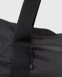 Sandqvist STREAM Weekender Bag noir — détail de la sangle et de la poche frontale zippée.