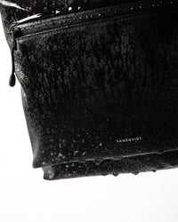 Sandqvist STREAM Rolltop Backpack L noir — détail du revêtement et de la poche zippée avec des gouttes d’eau.