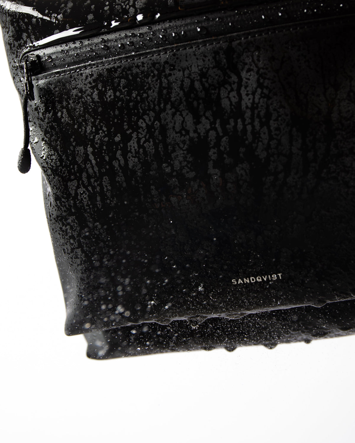 Sandqvist STREAM Rolltop Backpack L noir — détail du revêtement et de la poche zippée avec des gouttes d’eau.