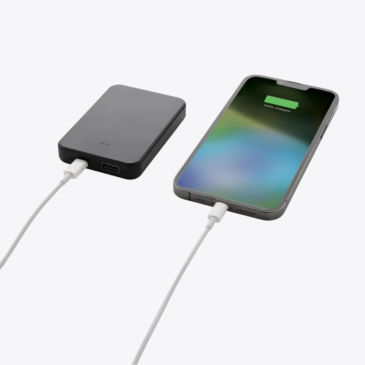 Batterie externe noire reliée par câble à un smartphone en charge