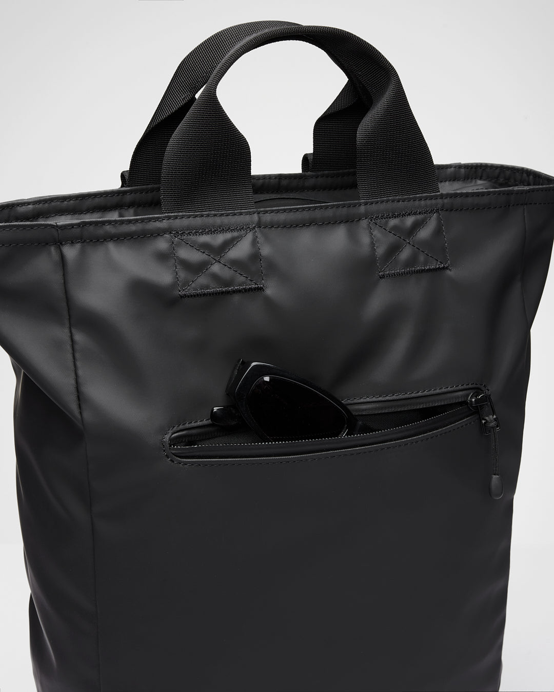 Sandqvist STREAM 2-Way Tote Backpack 16" noir — détail de la poche extérieure avec des lunettes illustrant le rangement.