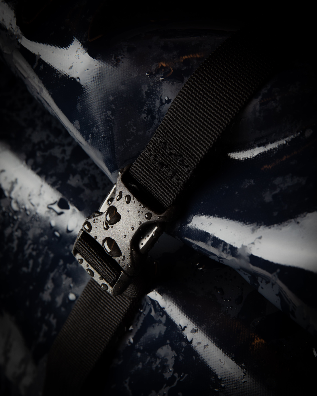 Sandqvist STREAM Rolltop Backpack 14" noir — gros plan studio sur la boucle, la sangle et le revêtement avec des gouttes d’eau.