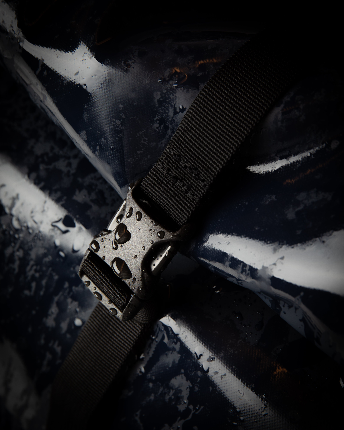 Sandqvist STREAM Rolltop Backpack 14" noir — gros plan studio sur la boucle, la sangle et le revêtement avec des gouttes d’eau.