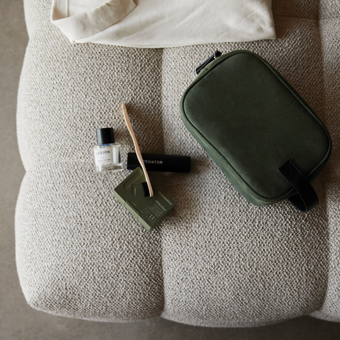 Trousse de toilette kaki posée sur un fauteuil avec des accessoires