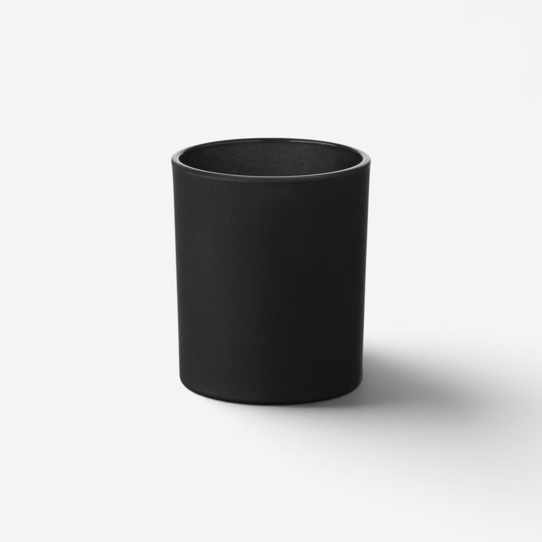 Bougie ronde dans un verre noir, vue de face