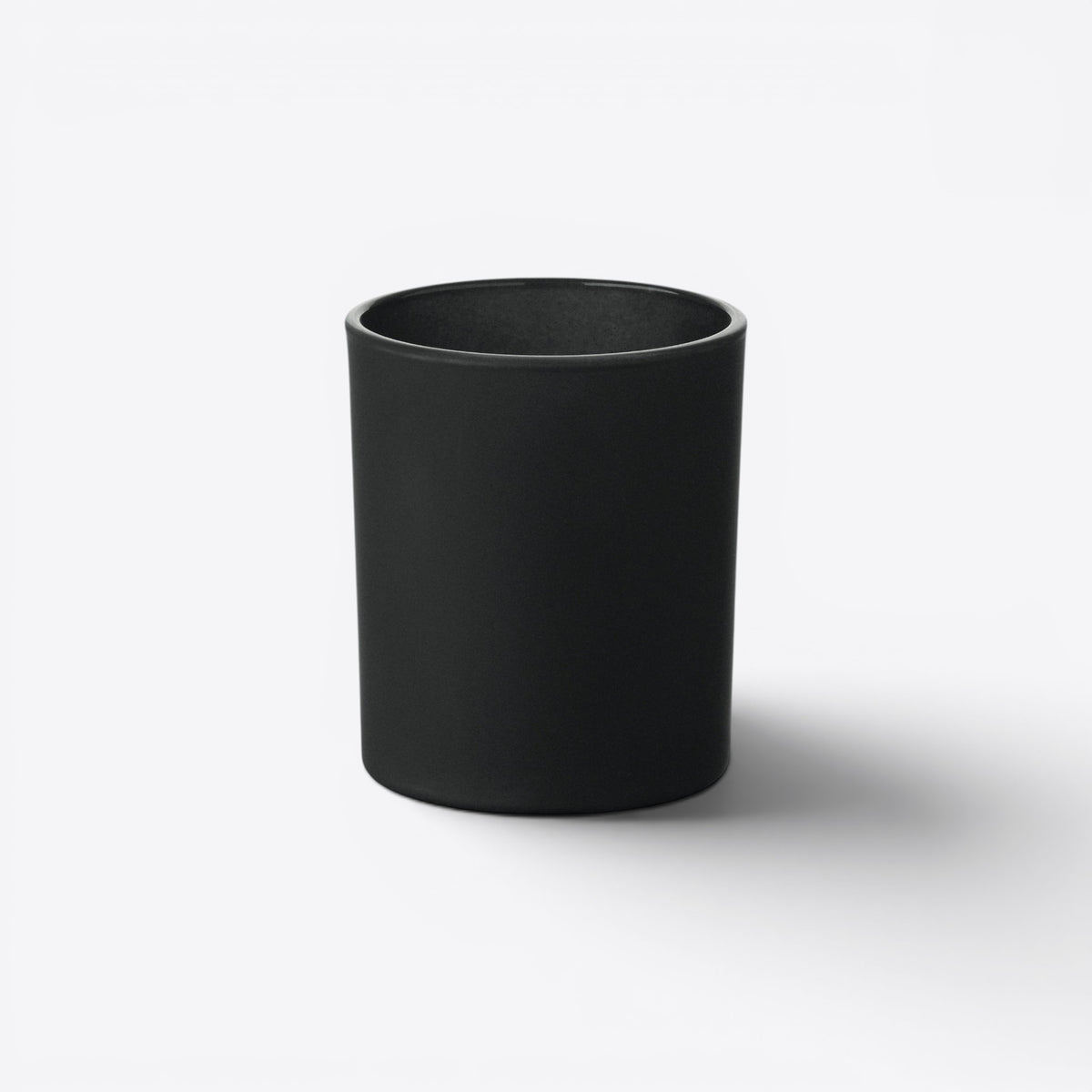 Bougie ronde dans un verre noir, vue de face