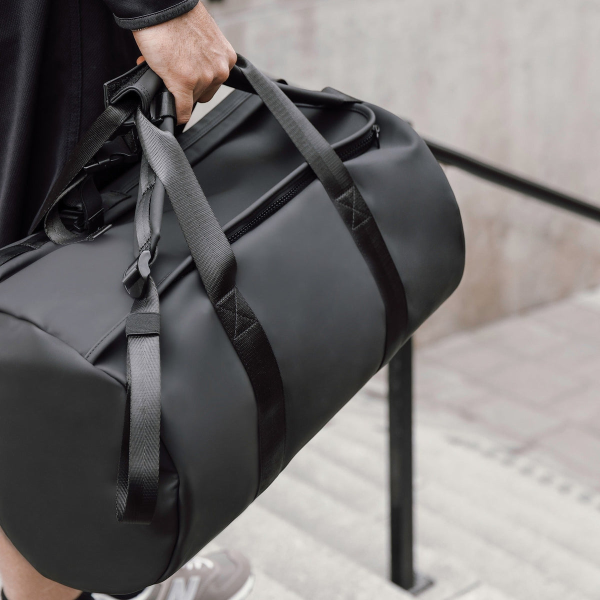 Personne portant un sac de voyage 2-en-1 gris anthracite à la main