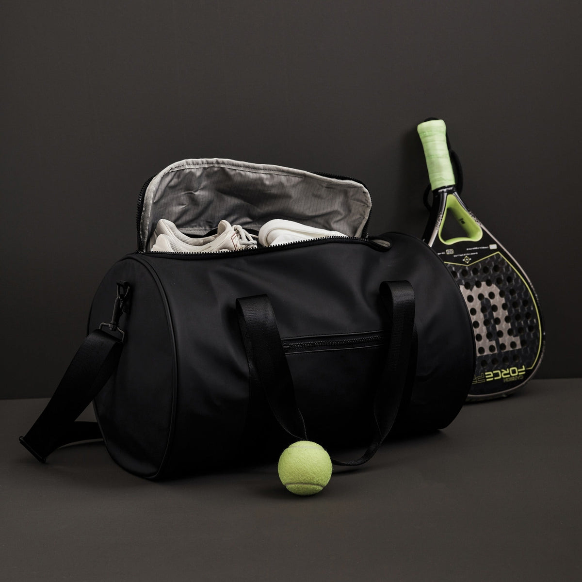 Sac de sport gris anthracite ouvert avec raquette et balle