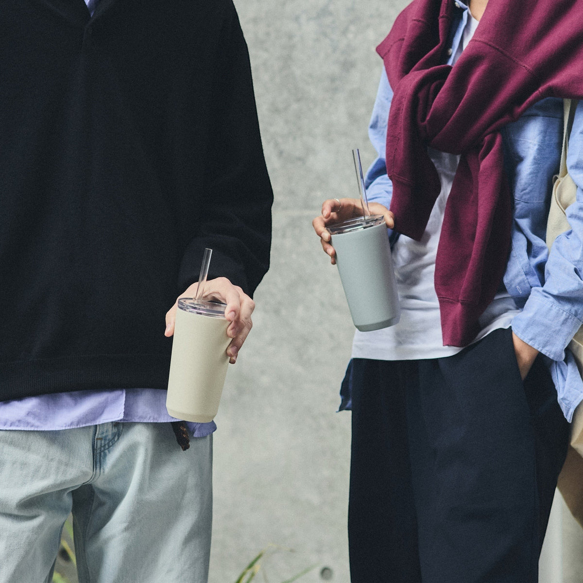 Deux personnes tenant des gobelets Kinto avec paille blanc cassé et bleu clair